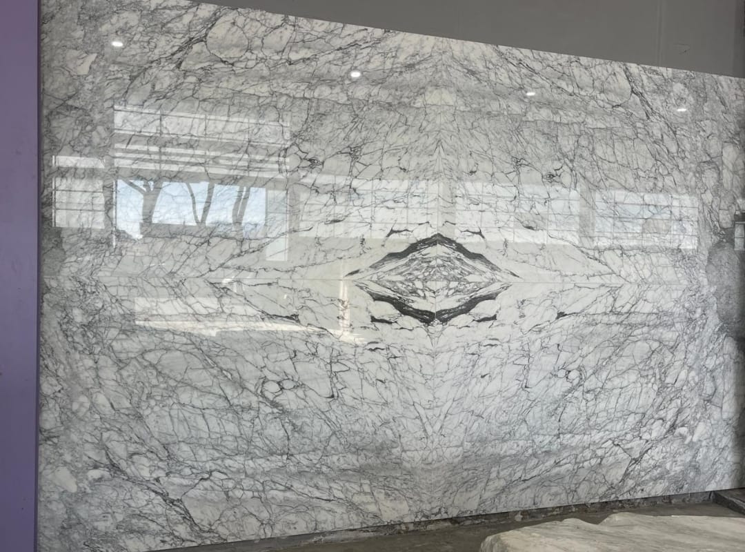 Pièce signature Showroom Temara — Statuario Carrara book-match, chantier ARCHIMAR livré 2026