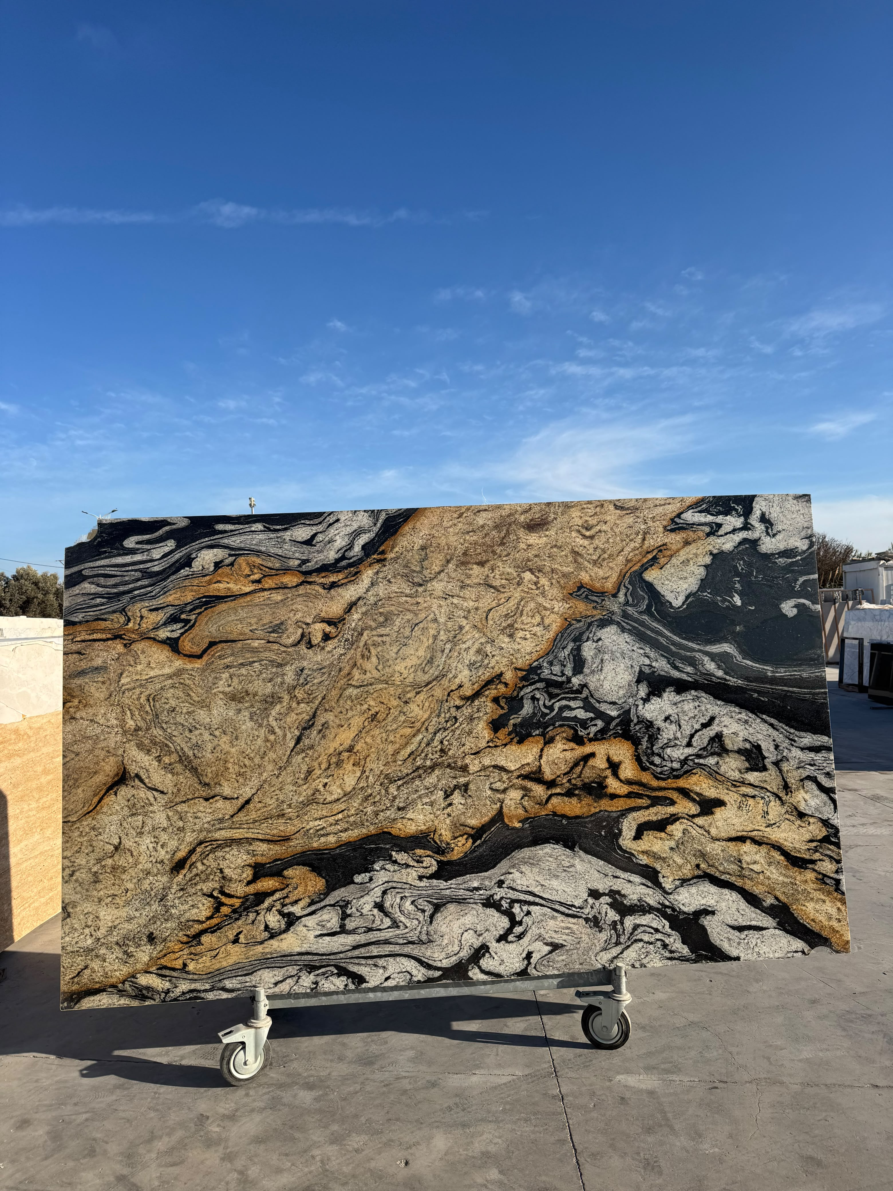Dalle Gold Cosmic — granit indien au dessin tourmenté : un grand champ or ocre à gauche, des bandes noires et blanches plissées à droite